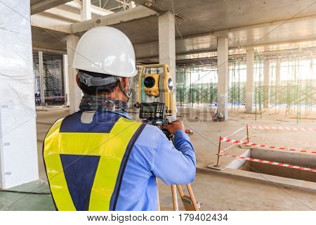 Surveyor engineer worker making measuring with theodolite equipment at construction site.