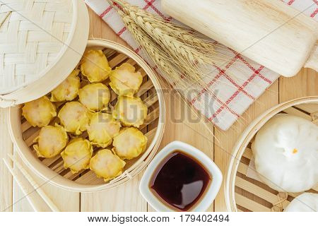 Steamed pork buns (chinese dim sum) in bamboo basket serve with chopsticks and napkin on wooden table background Top view with copy space and text.