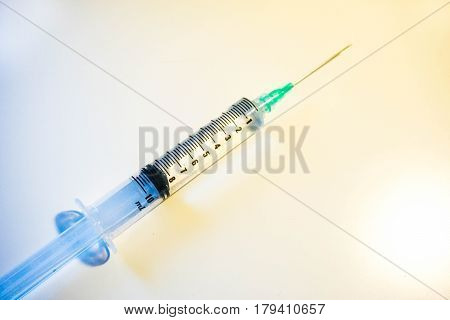 A medical syringe with a green tip is 8ml full of clear fluid against a white background