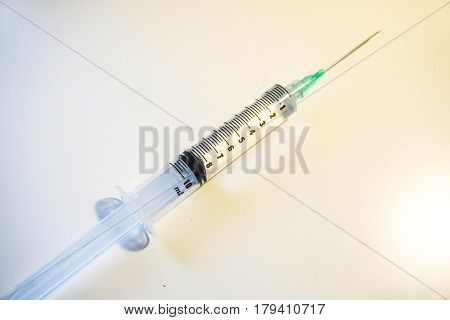 A medical syringe with a green tip is 8ml full of clear fluid against a white background