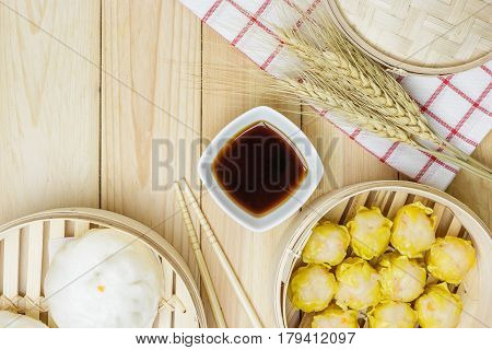 Steamed pork buns (chinese dim sum) in bamboo basket serve with chopsticks and napkin on wooden table background Top view with copy space and text.