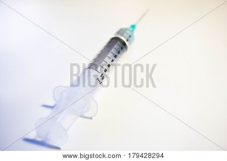 A green tipped syinge containing 2ml of water at a low angle