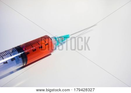 A green tipped syringe containing 4ml of red fluid (blood) from close up