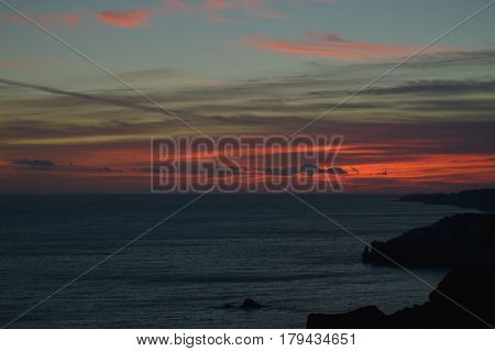 Sunny sunset over the sea. Bright clouds over the mountains.