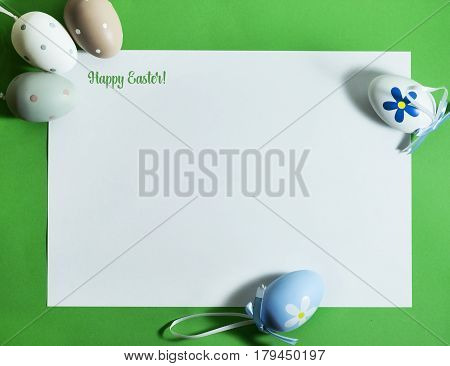 Easter composition with colorful eggs on a green background with copy space