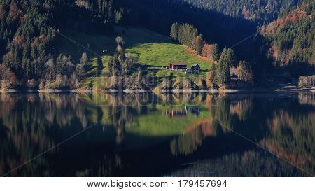 Autumn morning at lake Wagital Swiss Alps. Forest and green meadow mirroring in the lake.