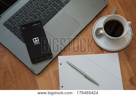 Nitra, Slovakia, march 28, 2017: Dolby Atmos application in a mobile phone screen. Workplace with a laptop, an earphones, notepad, pen and coffee on wooden background