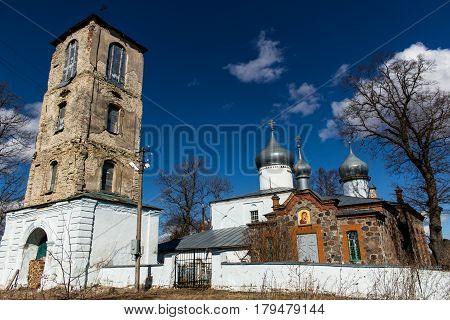 Orthodox Christian church next to the bell tower. Ancient buildings against a blue sky with white clouds. Sunny spring day. Deepest feeling of peace and tranquility.