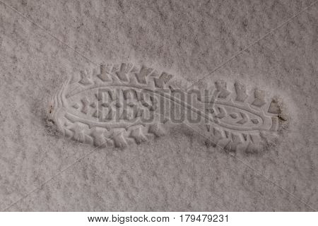 Footprint of the boot on white clear snow. Snow is very fluffy. Winter returned at the end of March.