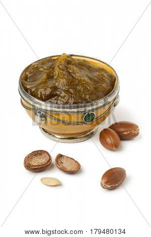 Bowl with traditional Moroccan black argan soap and nuts on white background