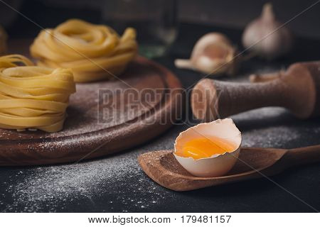 Raw homemade pasta and ingredients for cooking on a black background. Uncooked noodles with flour egg and spices. Food and culinary concept.