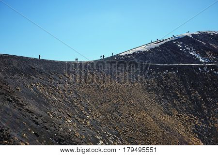 tourists are walking on the ridge of one of the hundreds craters in the Etna Park - Sicily