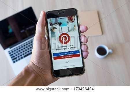 CHIANG MAI THAILAND - JAN 282017: A man holds Apple iPhone with Pinterest application on the screen. Pinterest is an online pinboard that allows people to pin their interesting things.