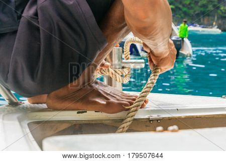 A young Man put down anchor to the sea and mooring rope tied around steel anchor on boat or ship