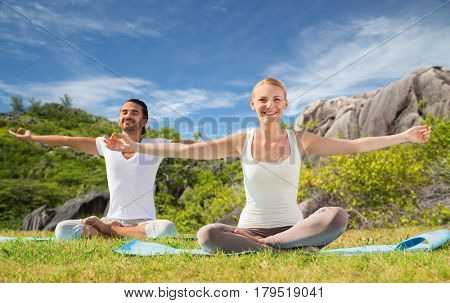 fitness, sport and people concept - happy couple making yoga exercises outdoors