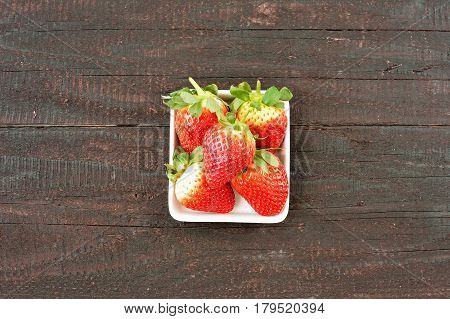 Strawberry fruit on wood background. Forest fruit in white idaeus. Delicious fresh berries.