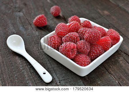 Raspberry fruit on wood background. Forest fruit in white idaeus and spoon. Delicious fresh berries.