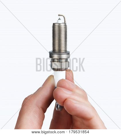 Mechanic holds a spare part spark plug in his hand. Auto part spark plug close-up on a white background.
