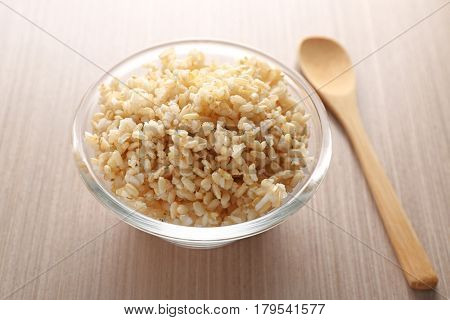 Glass bowl full of brown rice on wooden table