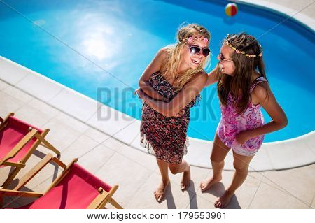 Beautiful appy girls smiling by the pool and enjoying summer