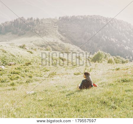 Young woman is resting on summer mountain meadow in sunny day.