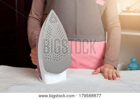 Young woman in uniform with steam iron