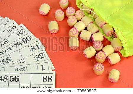 top view of details of Russian vintage game Bingo or Lotto with white paper cards in the cells are written black numbers small wooden barrels which read pink numbers green bag on the table red color