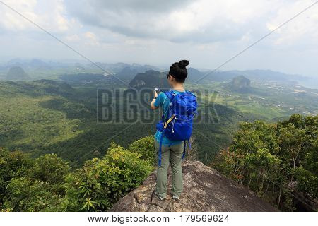 successful woman hiker taking photo with cellphone hiking on mountain peak