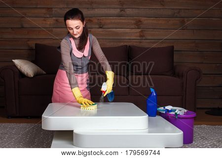 Woman in uniform and rubber gloves cleans table