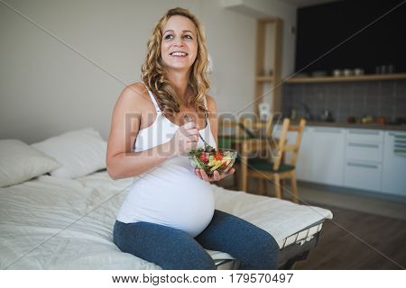 Beautiful pregnant woman eating healthy food and salads