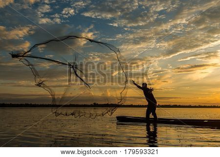 Fisherman is fishing by using fishing net on the river during evening sunset