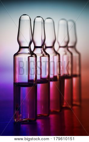 Row of ampulas with medicine on purple background