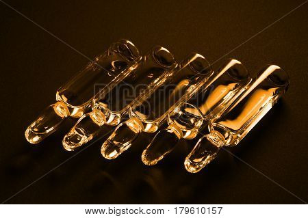 Row of ampulas with medicine on dark background