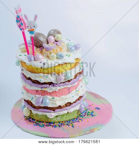 Naked cake with five layers in different flavor and small eggs chocolate attached to it in different color.