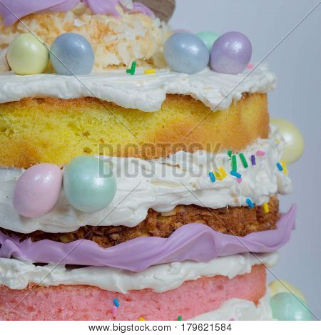 Naked cake with five layers in different flavor and small eggs chocolate attached to it in different color.