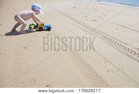Baby boy pushing his beach toys over the sand. El Rompido Cartaya Huelva Spain