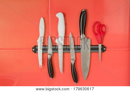 Knife magnet holder with different knives on the red tile background