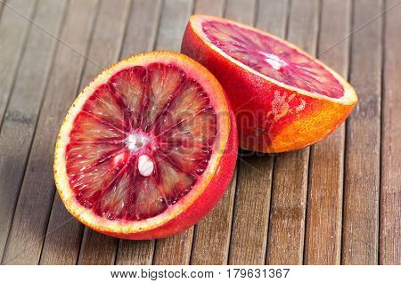 the juicy Blood orange cut in half on a wooden striped brown background