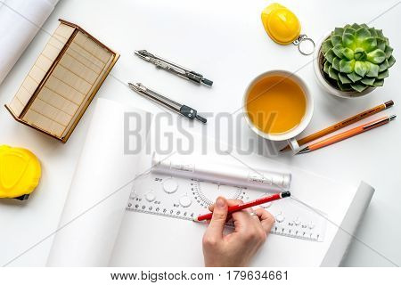 architect working desk with cup of tea, hands and project on white background top view