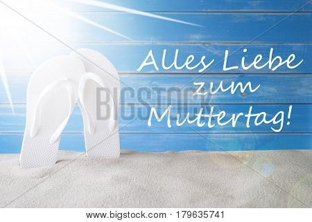 German Text Alles Liebe Zum Muttertag Means Happy Mothers Day. Sunny Summer Greeting Card With Sand And Flip Flops. Blue Vintage And Shabby Chic Wooden Background.