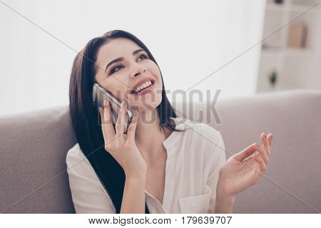 Portrait Of Pretty Laughing Woman Sitting On Sofa At Home  And Talking On Phone With Her Best Friend