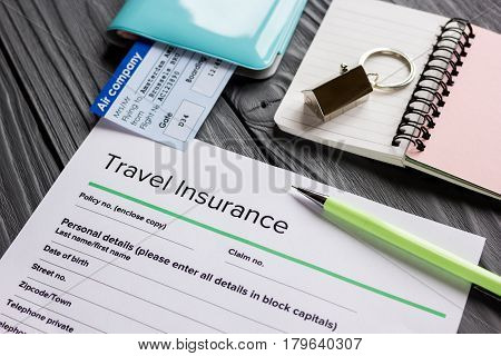 Travel insurance application form with flight tickets and passport on gray wooden desk background