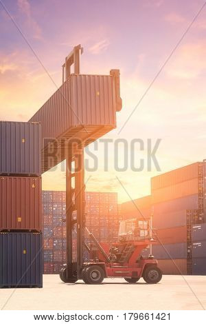 Forklift Truck Lifting Cargo Container In Shipping Yard Or Dock Yard Against Sunrise Sky With Cargo