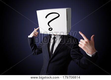 Businessman standing and gesturing with a cardboard box on his head with question mark