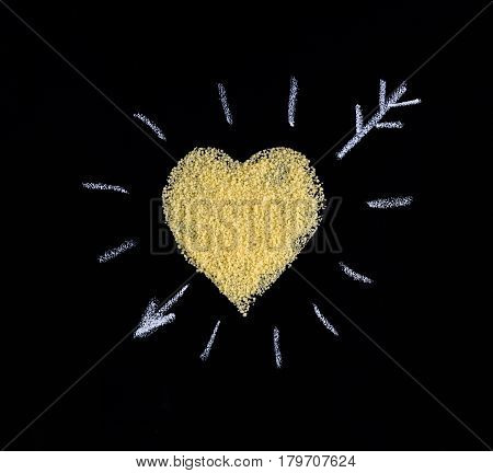 Heart made of couscous on a black background. I like couscous. Heart with an arrow drawn in chalk