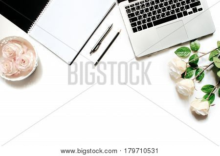 Modern minimalistic work place. White office desk table with laptop keyboard, pen, office plant, white roses, vintage tray. Top view with copy space, flat lay