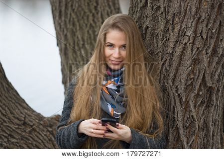 Portrait Of A Beautiful Girl With A Phone In Early Spring Outdoors.