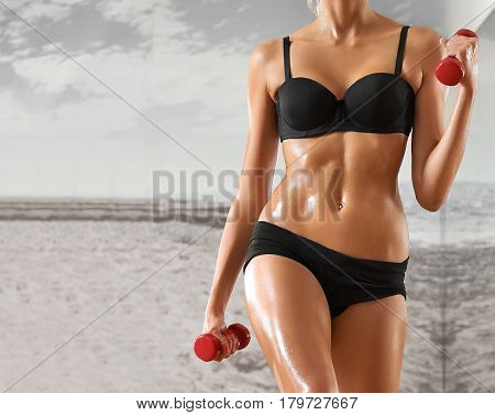 Sexy, athletic, blonde woman in the gym, against the background of the mirror, with dumbbells in hands. Sports, sportswear, health, a beautiful body, body Parts