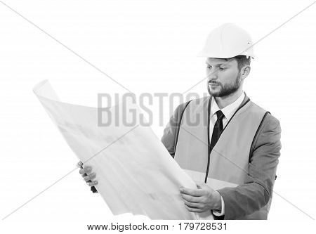 Working concentration. Black and white shot of a serious male constructionist in a hardhat and safety vest looking at the blueprints on white background professionalism success development concept