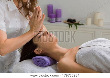 Head and face pummeling massage in spa. Female beautician work in wellness center. Professional massagist make relax healthy procedure to beautiful indian girl in cosmetology cabinet or beauty parlor.
